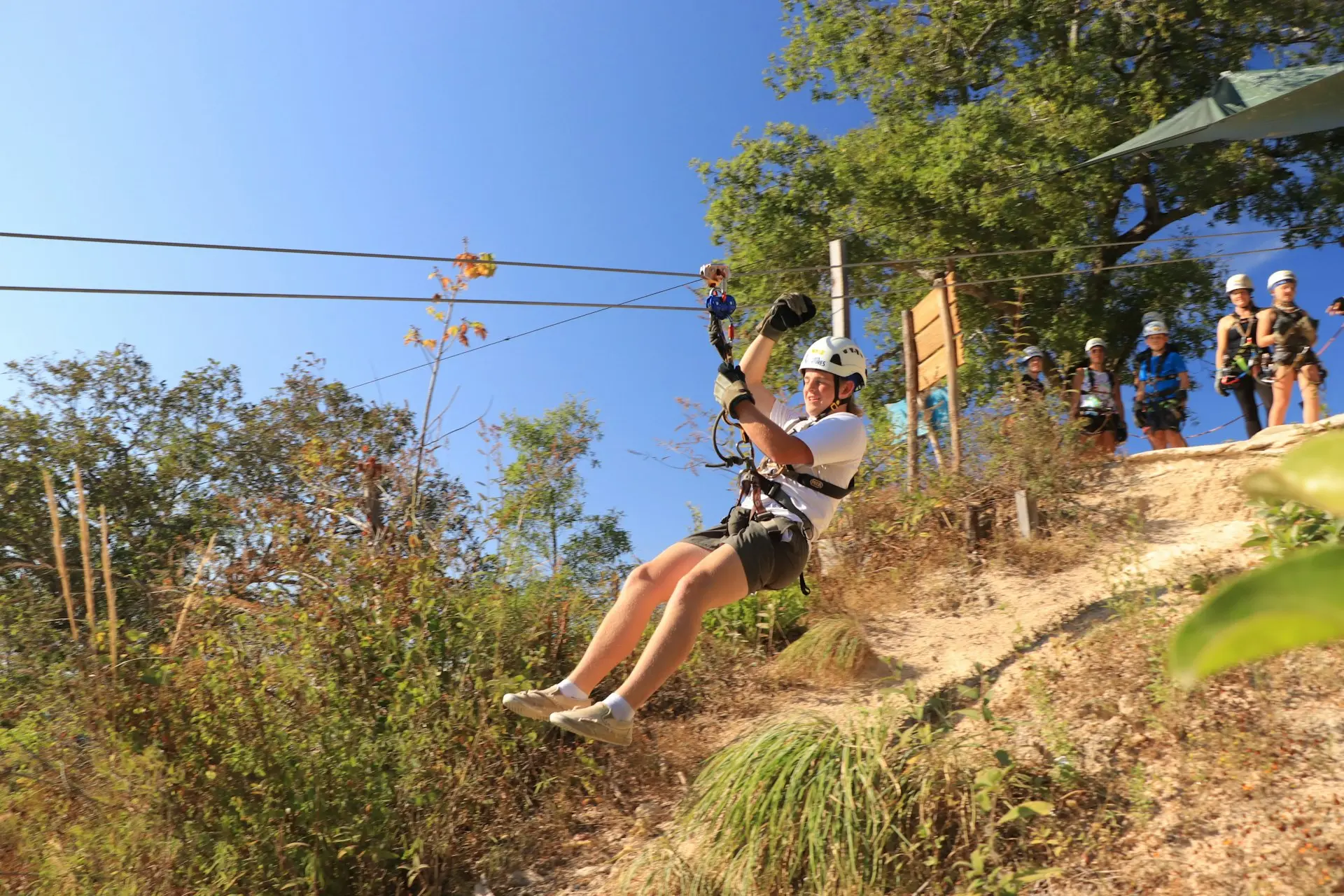 a man riding a zip line on top of a lush green hillside